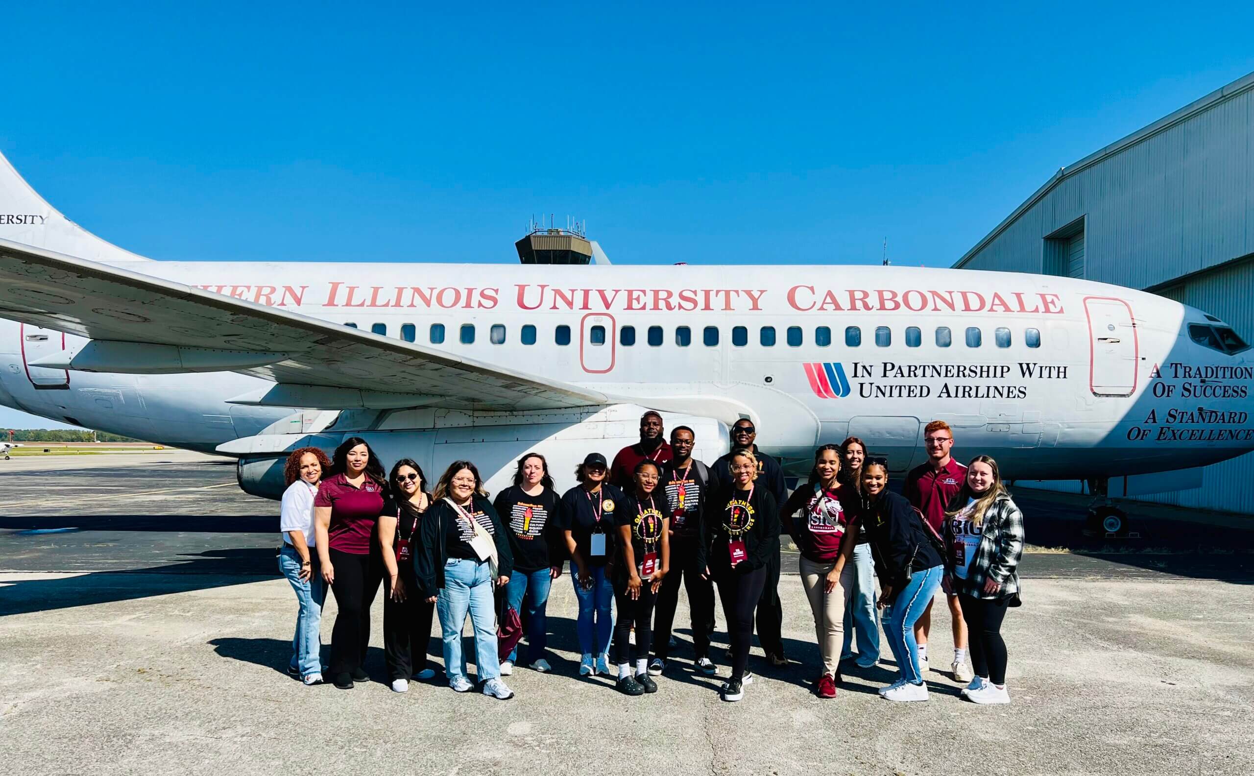 A group of students pose in front of an airplane