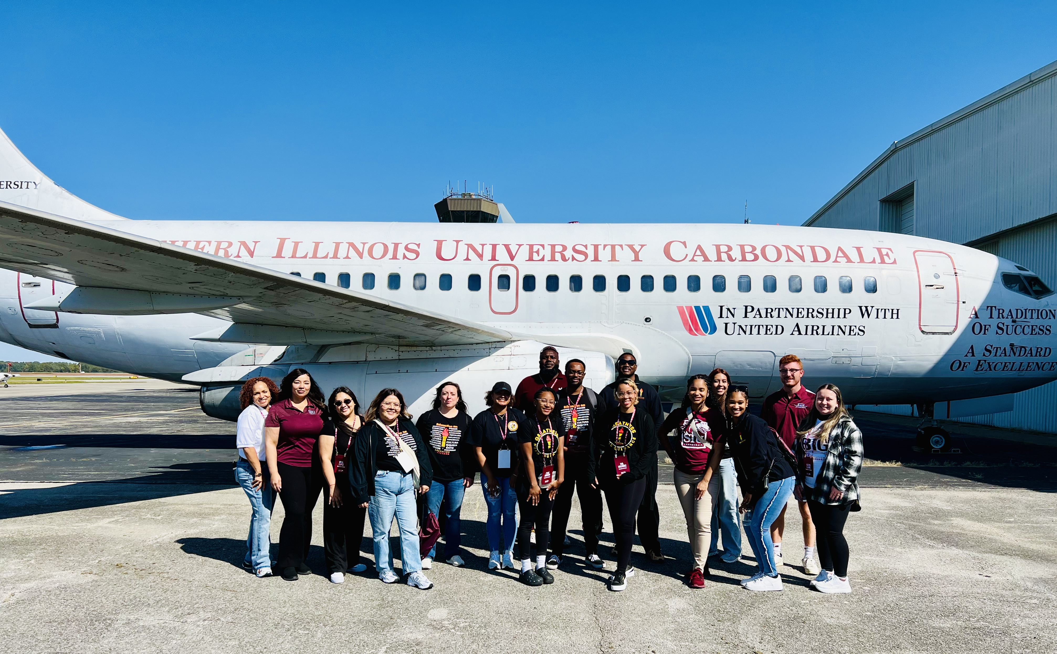 A group of students pose in front of an airplane