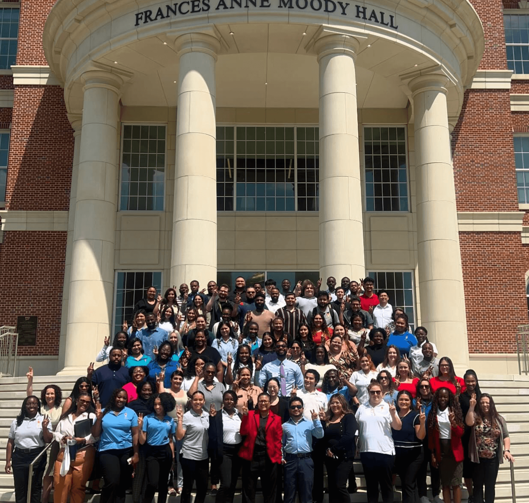 A group of students pose in front of Frances Anne Moody Hall